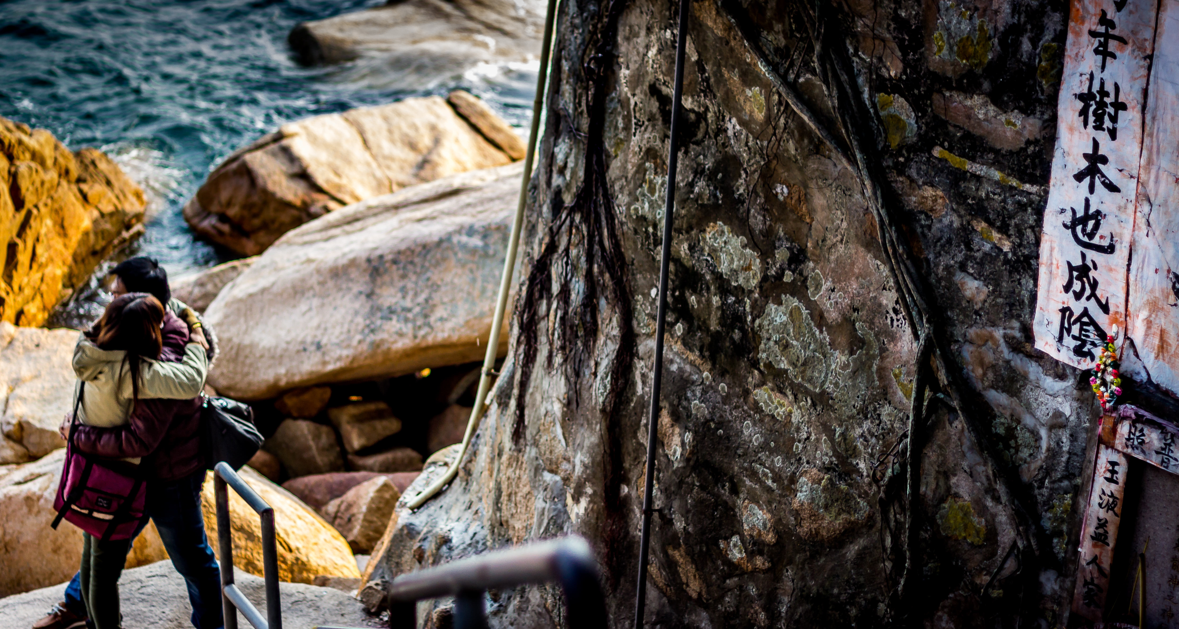 A couple embraces on the rocky coast, Hong Kong