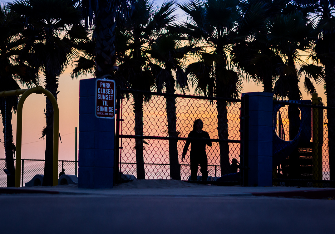 Silhouette at dusk through chain-link, Venice Beach